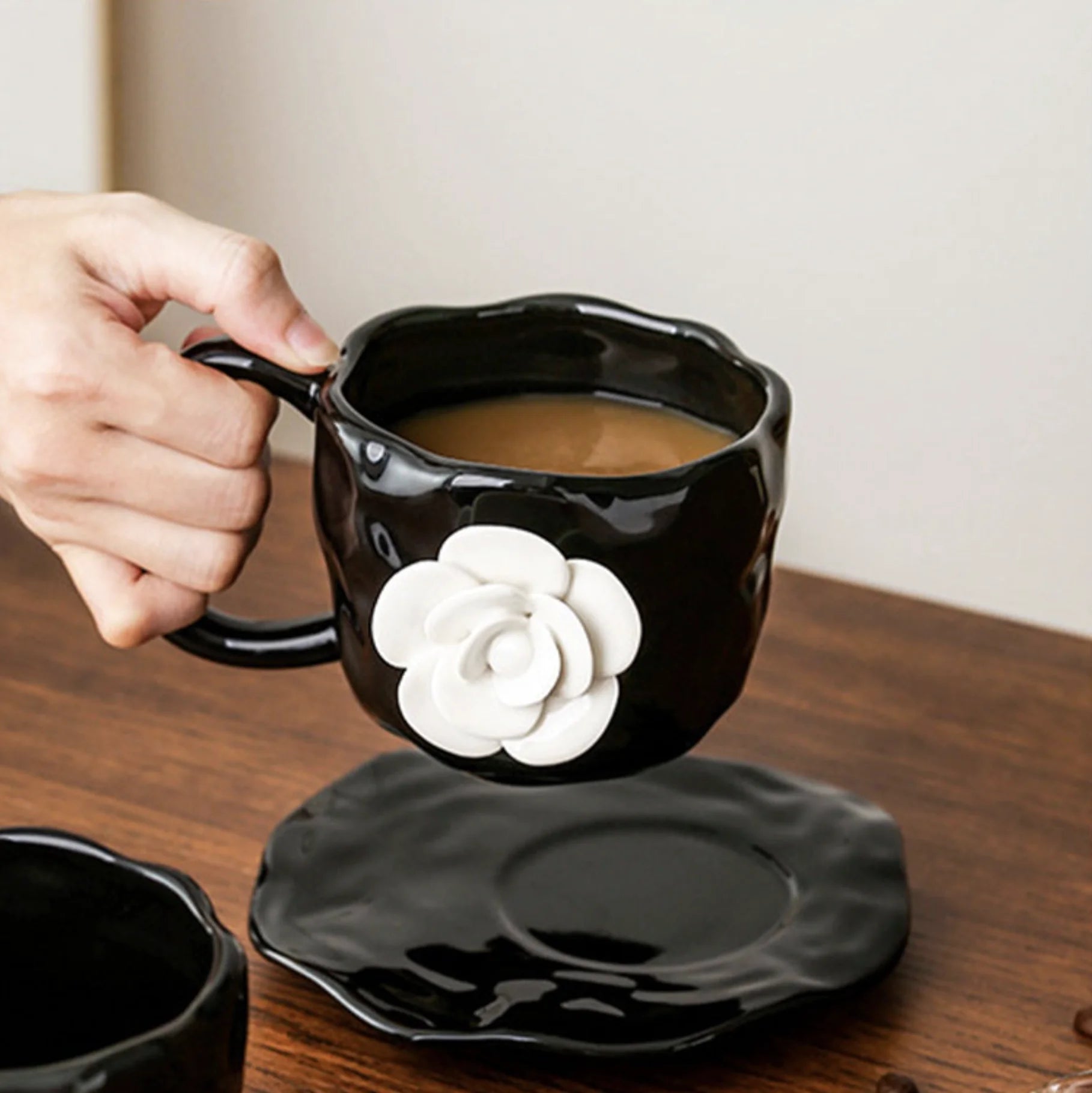 Hand holding the Textured Black Camellia Mug filled with coffee - RoomDen