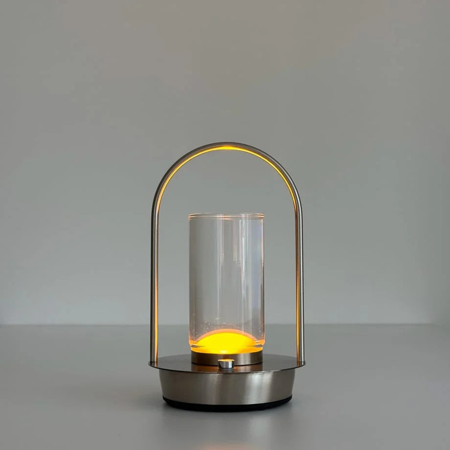 The Minimalist Arch Metal Portable Table Lamp turned on with a warm, yellow light. - RoomDen