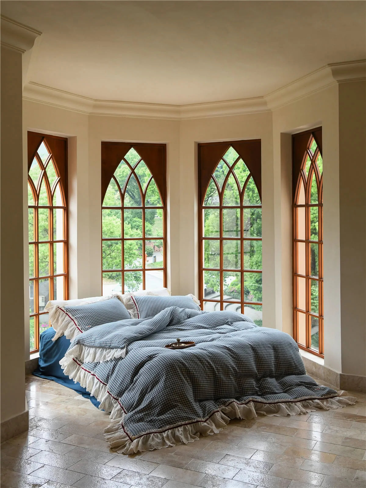 Blue gingham washed cotton bedding set with lace ruffles passing the daylight test in a sunlit room with arched windows. — RoomDen