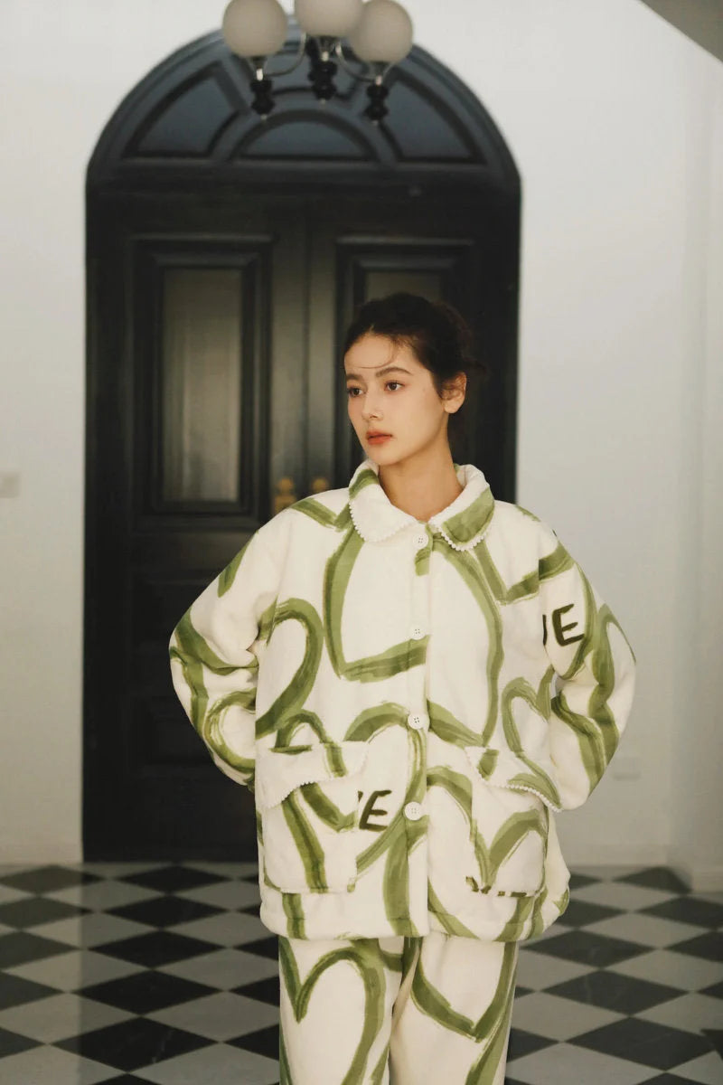 Model standing in a hallway with checkered floors, wearing the full green and white fleece pajama set - RoomDen.