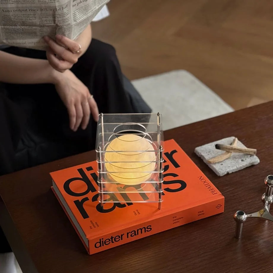 Lifestyle scene with the Crystal Clear Caged Lamp on a coffee table while a person reads a newspaper - RoomDen