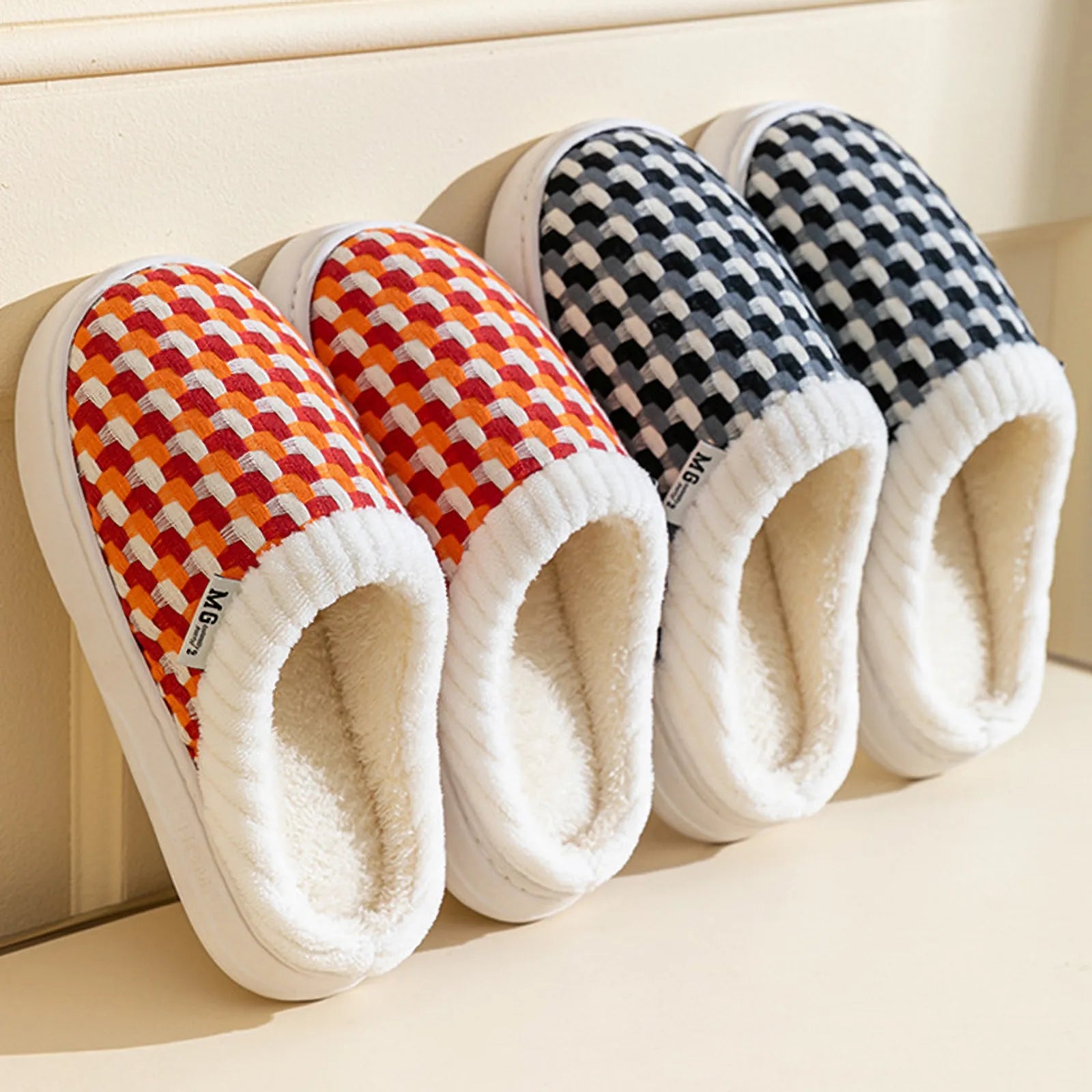 Orange and red woven checkered pattern plush slippers leaning against wall