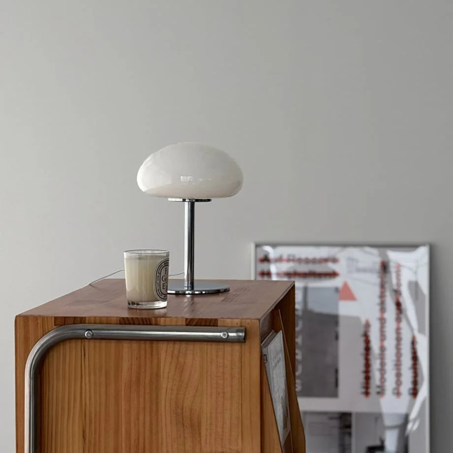 The white mushroom accent lamp styled on a wooden console with a poster in the background - RoomDen.