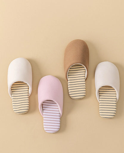 Top view of four pairs of cotton house slippers in white pink brown and beige arranged neatly