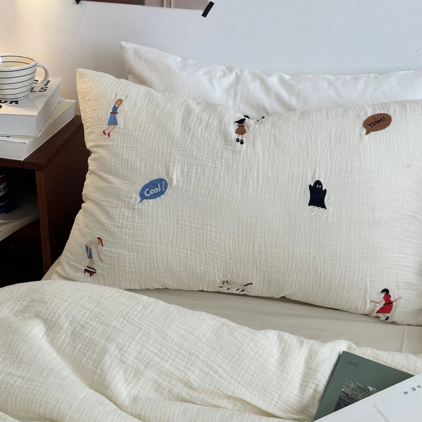 Close-up of a pillowcase from the whimsical embroidered bedding set, showing the crinkled cotton texture and character details.
