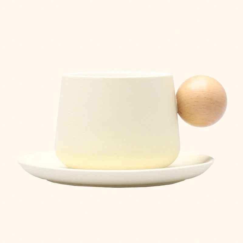 A studio shot of the Creamy White Frosted Ceramic Mug and Saucer Set with a wooden ball handle. - RoomDen