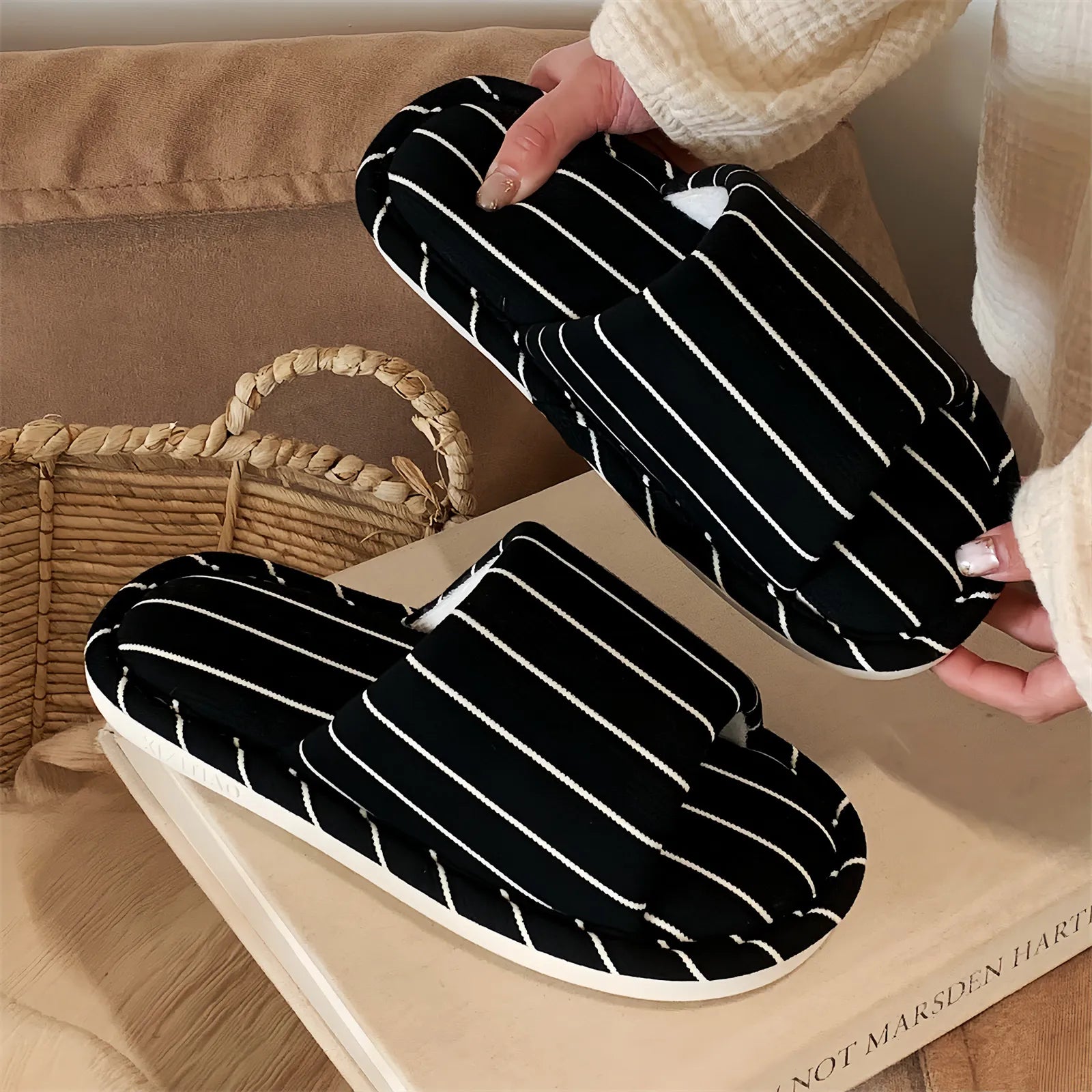 Black & White Striped slippers held against a neutral background, showing the contrast detail and plush lining.