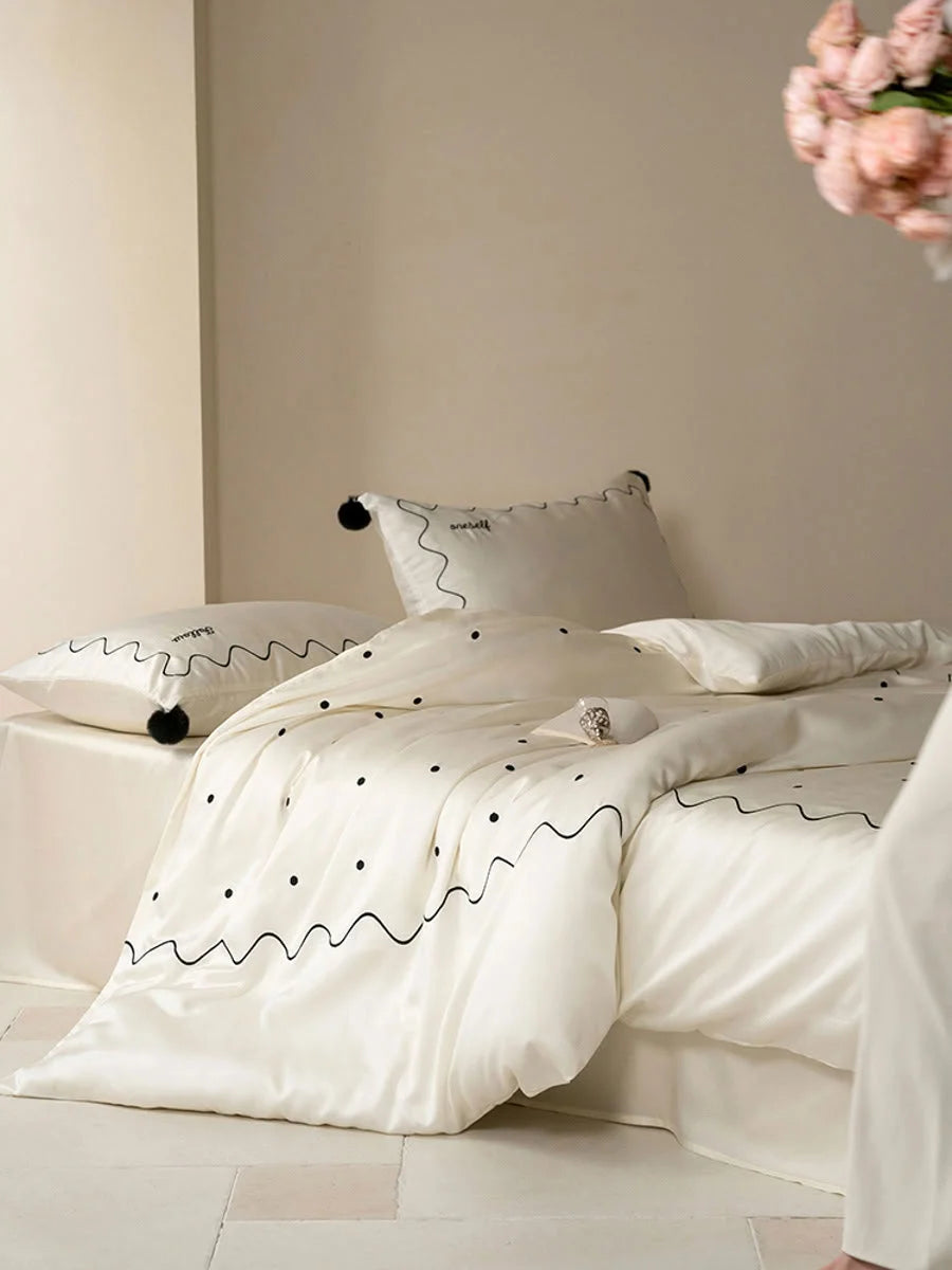 Lifestyle shot of the Creamy White & Black Tencel bedding set with a person holding flowers in the background. - RoomDen