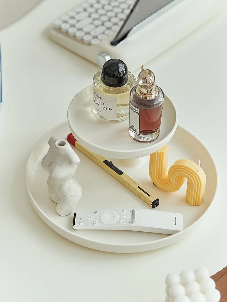 Top-down view of the cream white two-tier organizer tray holding a remote, candles, and perfume. - RoomDen