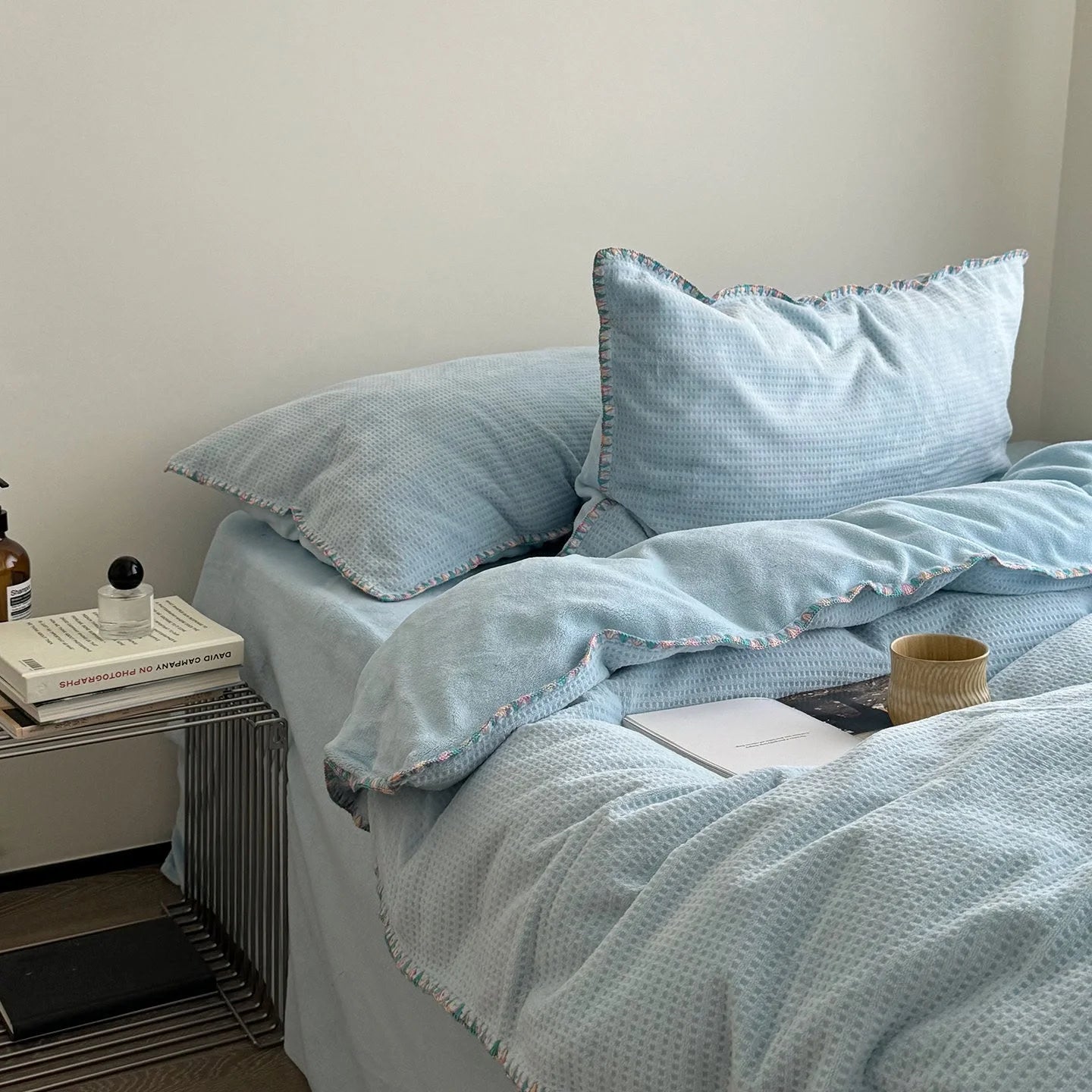 Full view of the Sky Blue Waffle Fleece Bedding Set on a bed next to a modern side table.