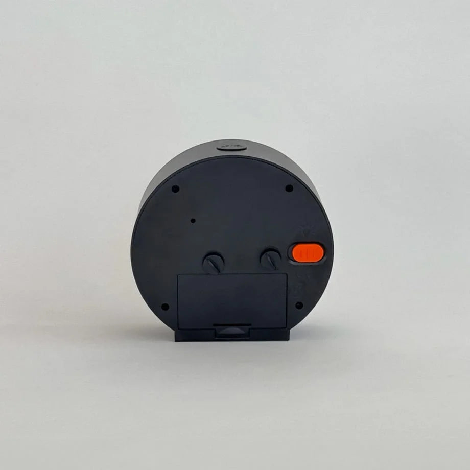 Back view of the black alarm clock showing the battery compartment and control dials. - RoomDen