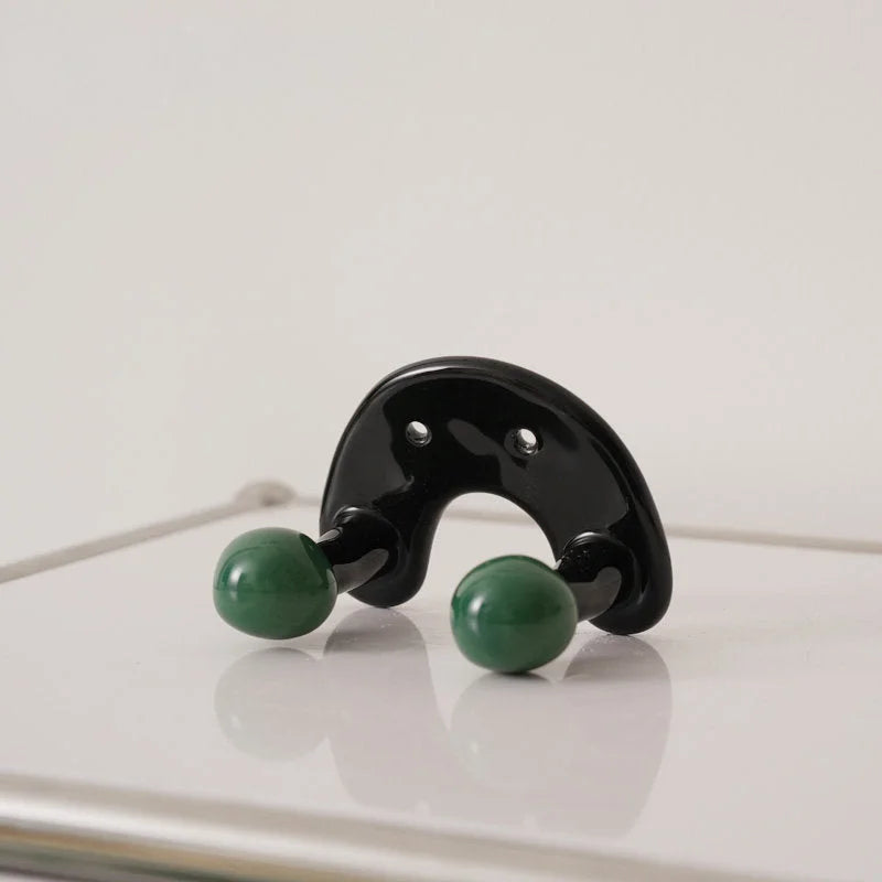 U-shaped black ceramic wall hook with two green balls, showing the glossy finish.