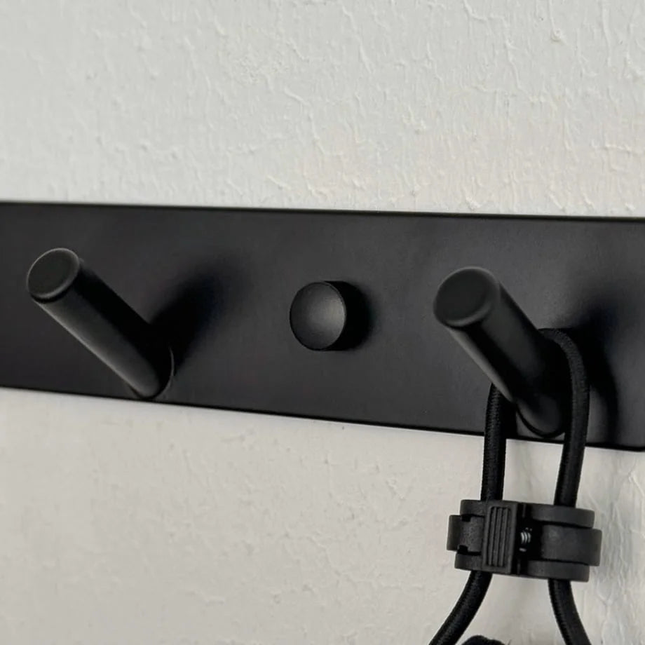 Detail shot of the black wall hook rack highlighting the peg design and mounting point cover - RoomDen.