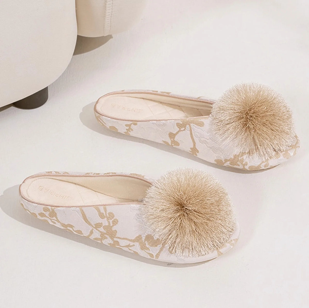 Pair of white and beige floral house slippers placed on floor - RoomDen
