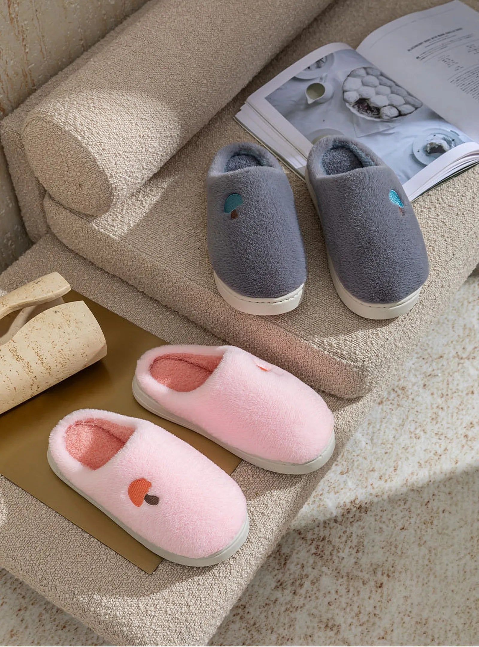 Pink and Grey Plush Mushroom Embroidered Fleece House Slippers on a boucle sofa with magazine - RoomDen