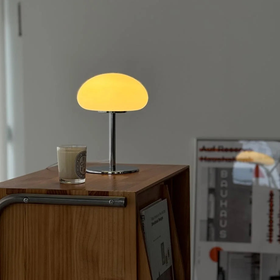 The warmly lit white mushroom lamp casting a soft glow on a wooden console table - RoomDen.