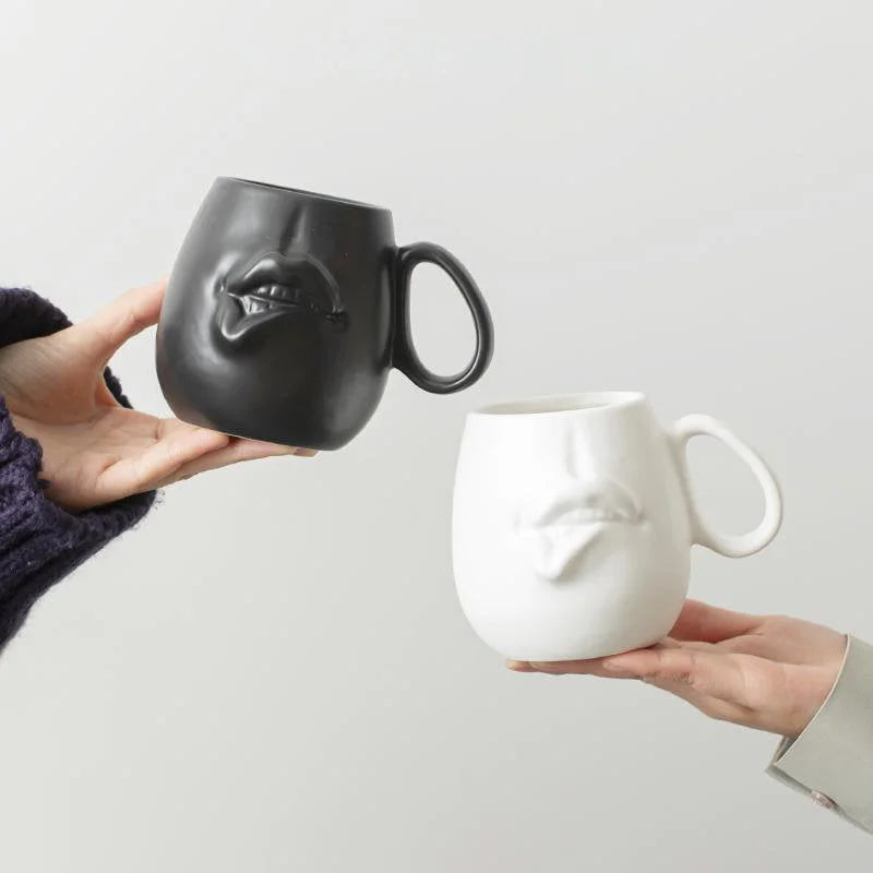 Two hands holding a matte black and a matte white Sculptural Abstract Face Ceramic Mug - RoomDen.