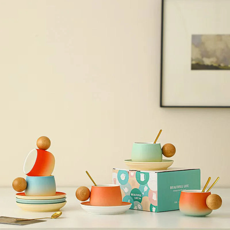 Lifestyle shot showing all color variants of the gradient ceramic mug and saucer sets, stacked and displayed with gift boxes. - RoomDen