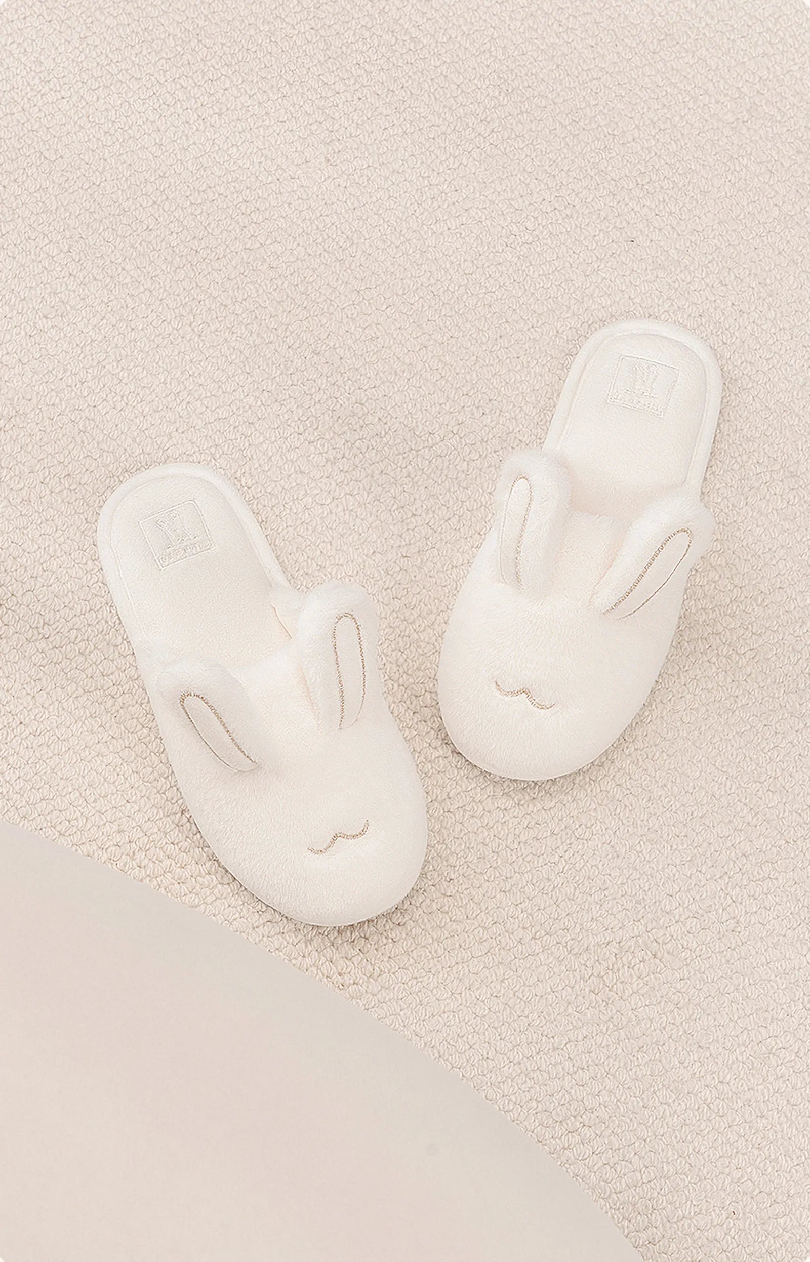 Top view of white bunny slippers showing embroidered face details - RoomDen