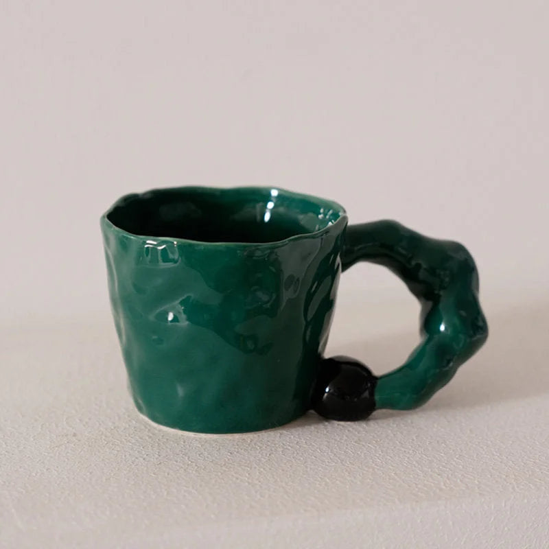 Front view of the emerald green textured ceramic mug with a black accent on its chunky handle - RoomDen.