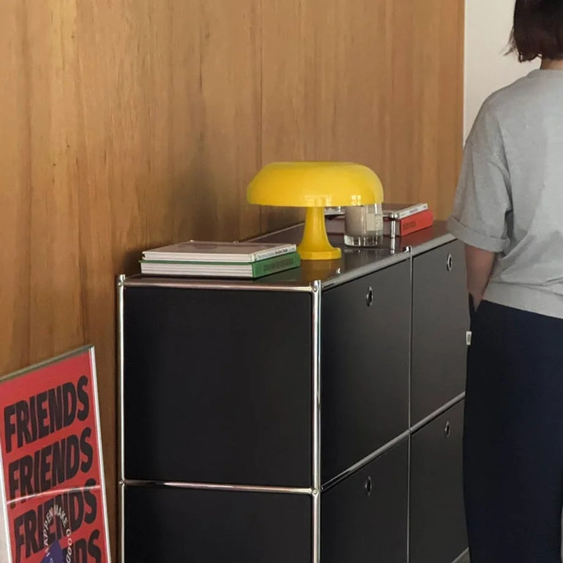 Marigold yellow mushroom lamp sitting on a black modular cabinet in a stylish room — RoomDen