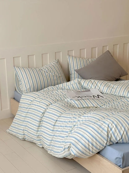 The Blue Striped variant of the Textured Pinstripe Washed Cotton Bedding Set on a bed with a blue sheet. - RoomDen