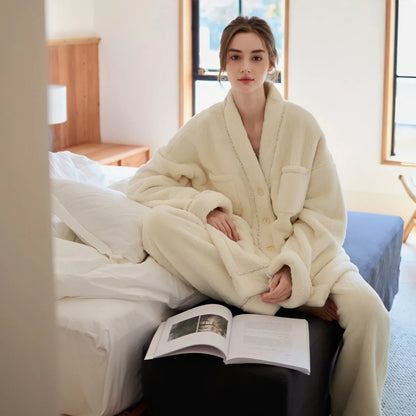 A woman sitting on a bed in a bright, modern room, wearing the cozy cream flannel fleece loungewear set - RoomDen.