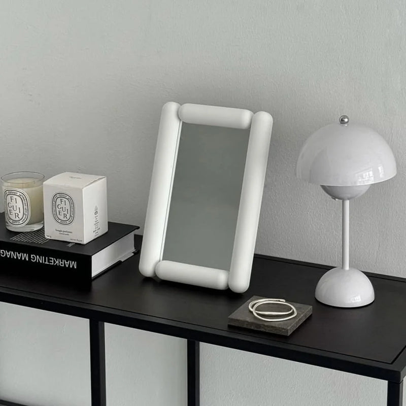 Angled view of the white minimalist pill-shaped vanity mirror — RoomDen