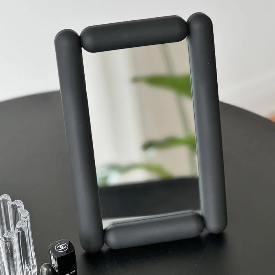 Angled view of the black minimalist mirror reflecting a plant. - RoomDen