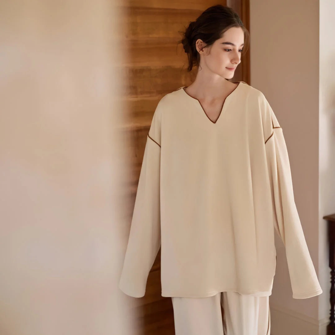 Model walking in the soft piped plush pajama set in a minimalist, warm-toned room. - RoomDen