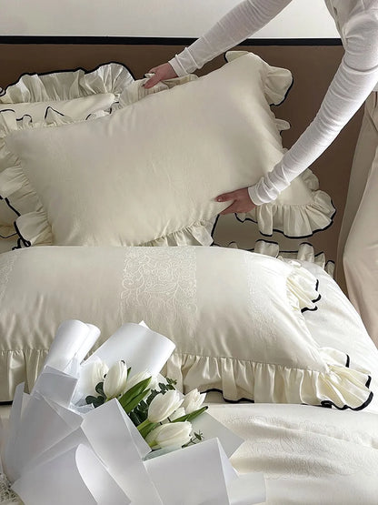 Detail shot of a person arranging the Cream White ruffled pillow, highlighting the jacquard pattern and texture - RoomDen.