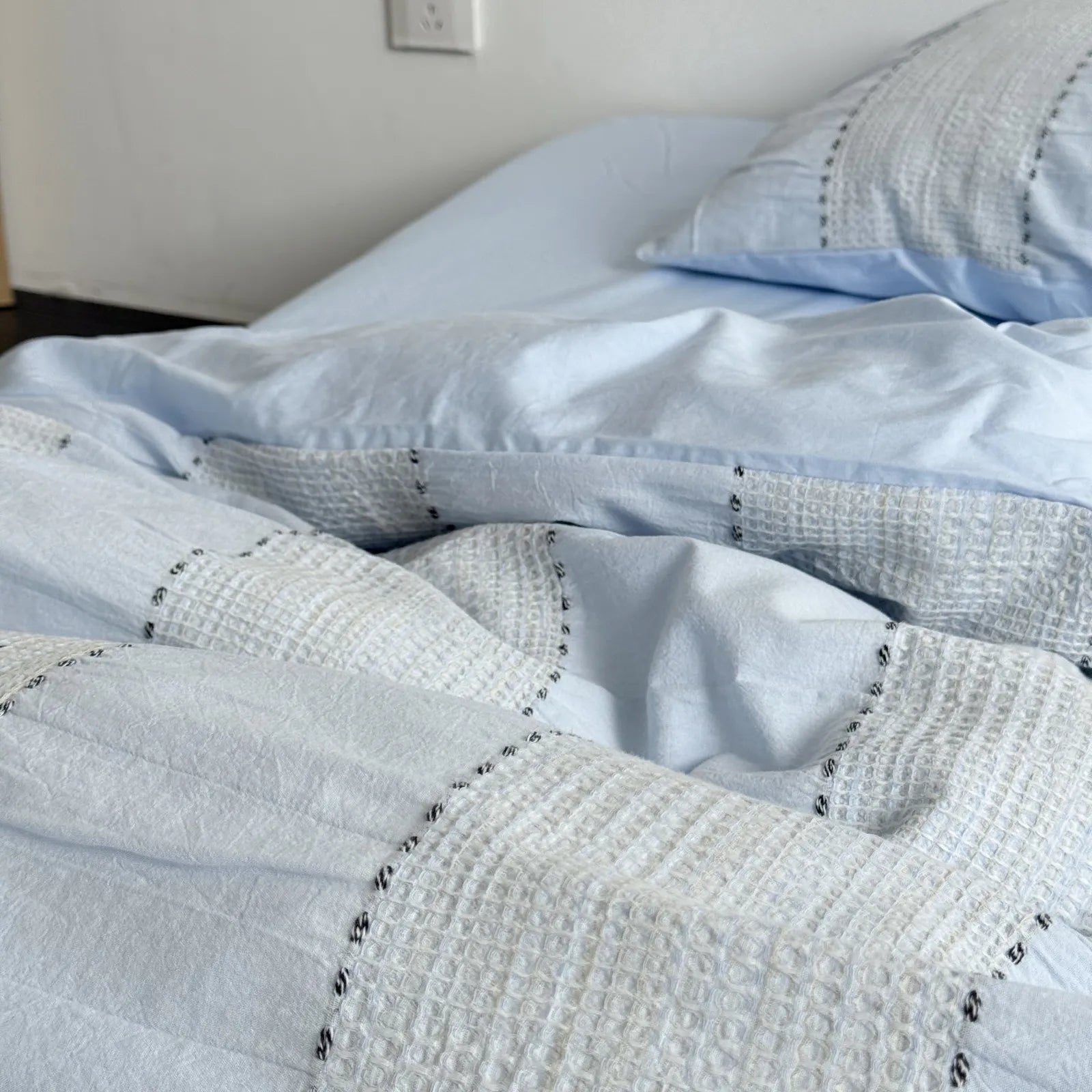 Close-up on the soft, wrinkled texture of the Sky Blue woven stripe duvet cover.