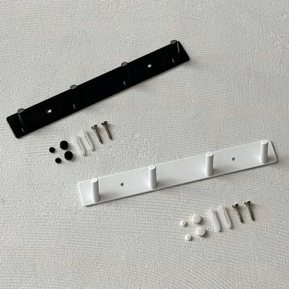 The black and white minimalist metal wall hook racks shown with included mounting hardware for drilling and adhesive options - RoomDen.