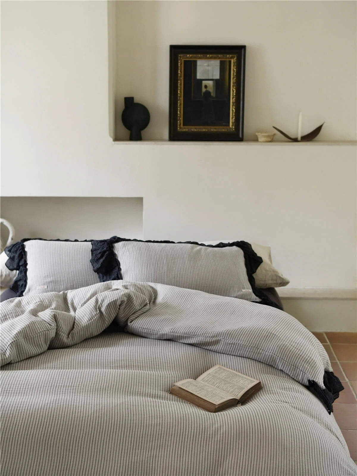 Front view of the bed showing the pinstripe duvet cover and pillows with black ruffles. - RoomDen