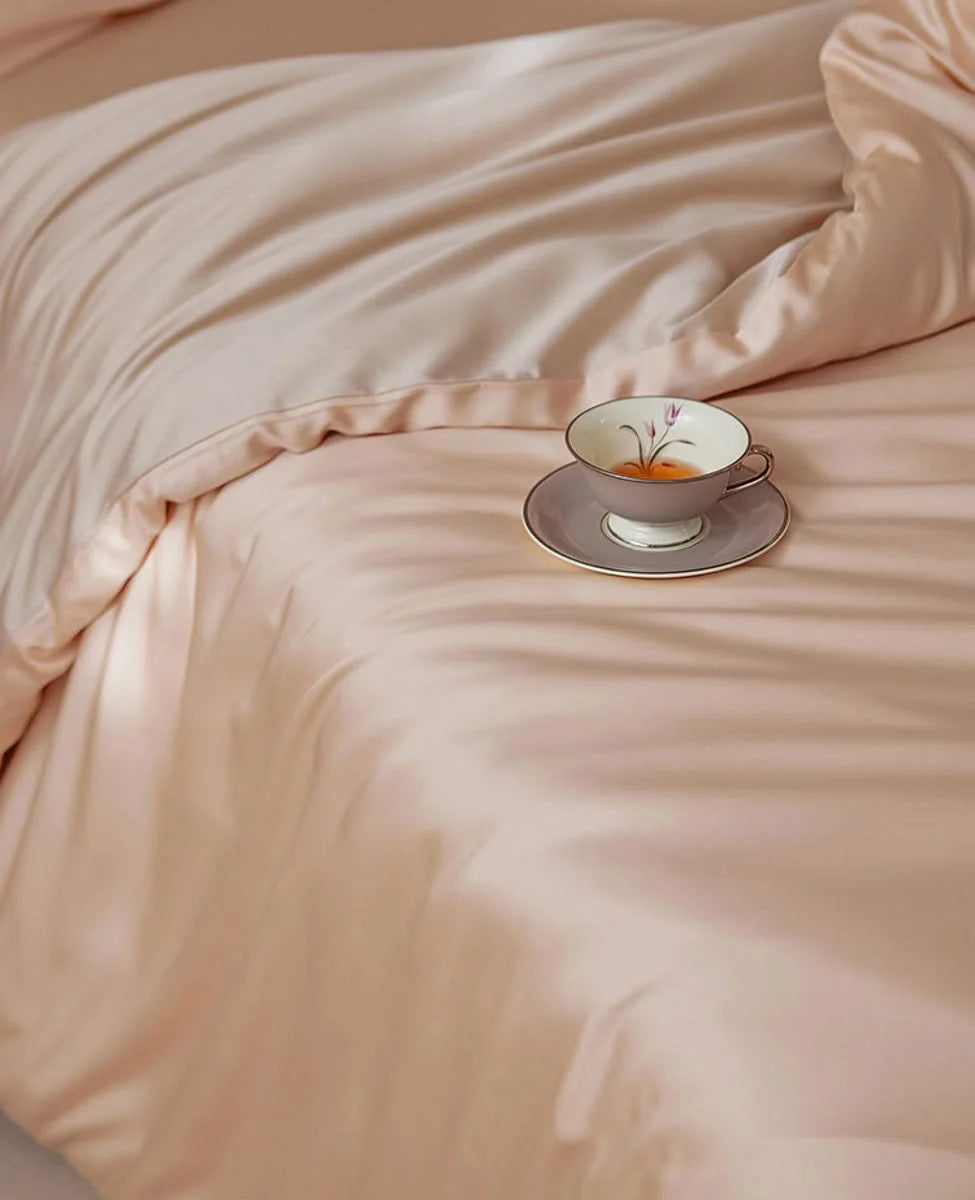 Close-up of a Blush Pearl silky Tencel duvet cover with a vintage teacup resting on it. - RoomDen