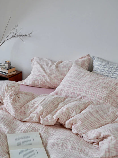 Close-up of the wrinkled texture of the Dusty Pink Plaid Washed Cotton Bedding Set with an open book - RoomDen