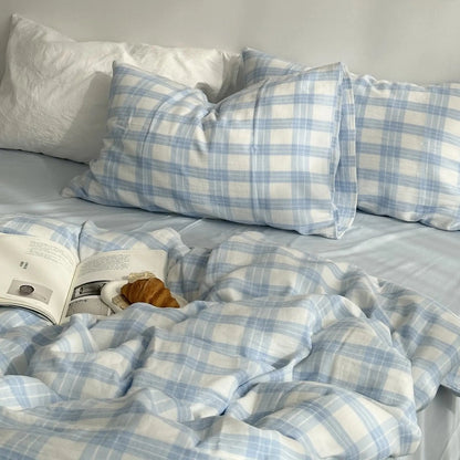 A cozy bed made with the sky blue and white gingham plaid duvet cover set, with white pillows in the background. - RoomDen