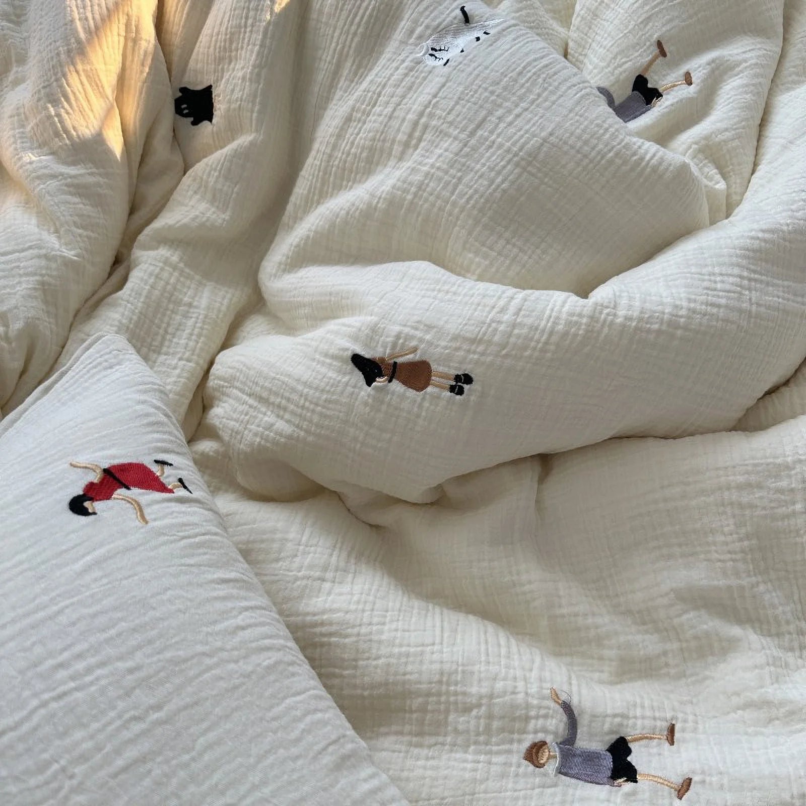An overhead view of the cozy, rumpled cream embroidered bedding, showing the soft texture under natural light.