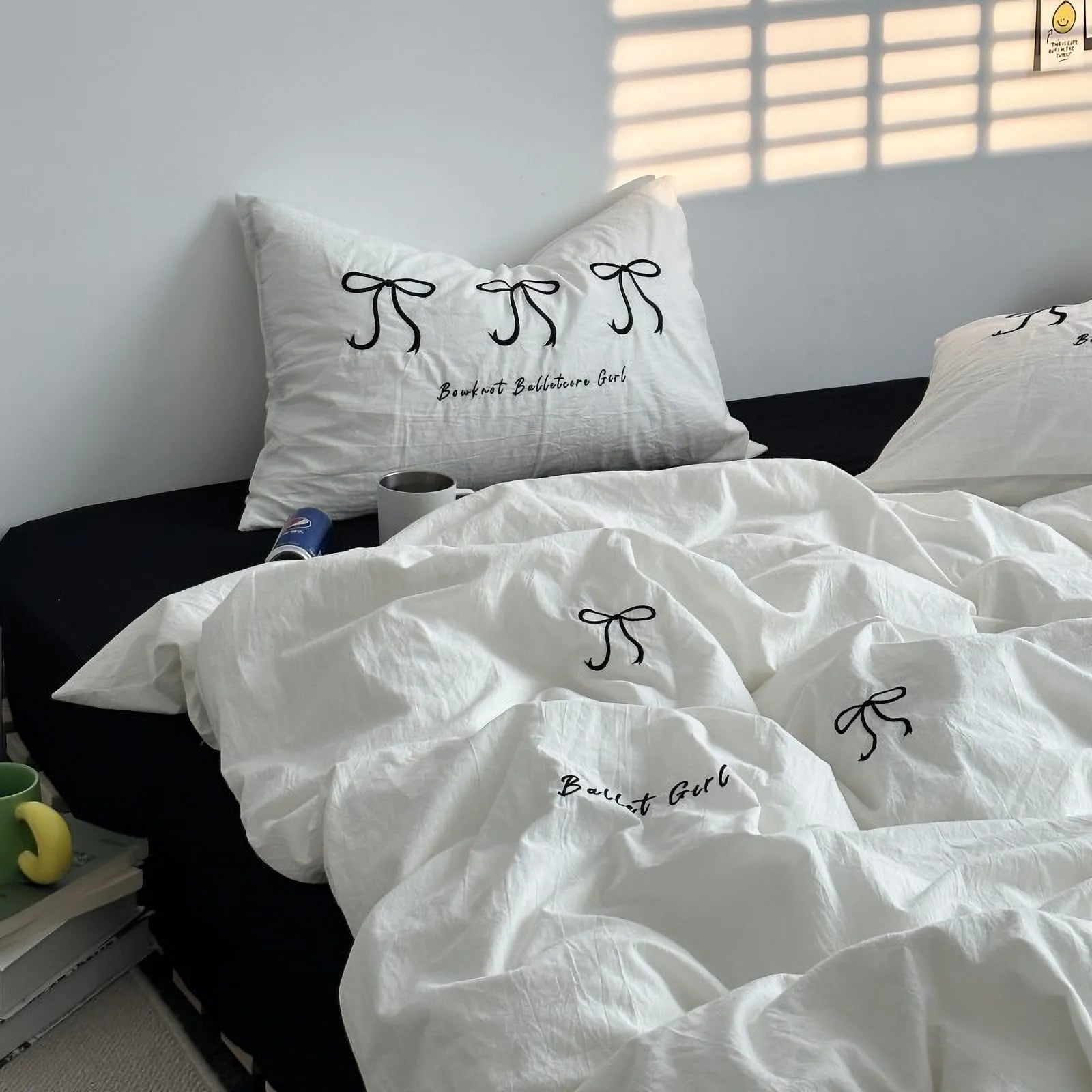 The white embroidered bowknot bedding set styled on a bed with a black fitted sheet for a high-contrast look.