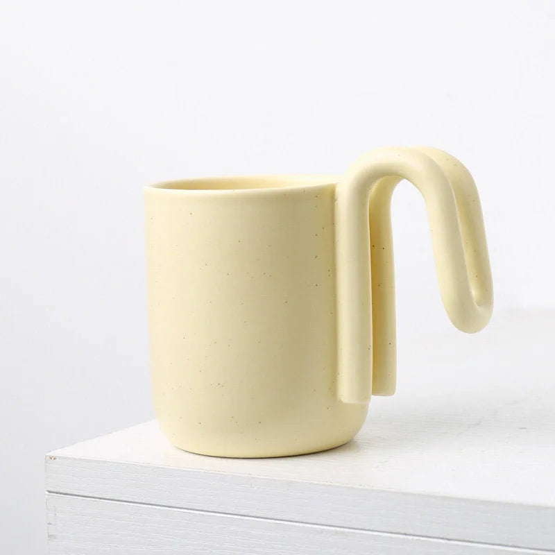 Side view of the Butter Yellow frosted ceramic mug with its unique loop handle - RoomDen