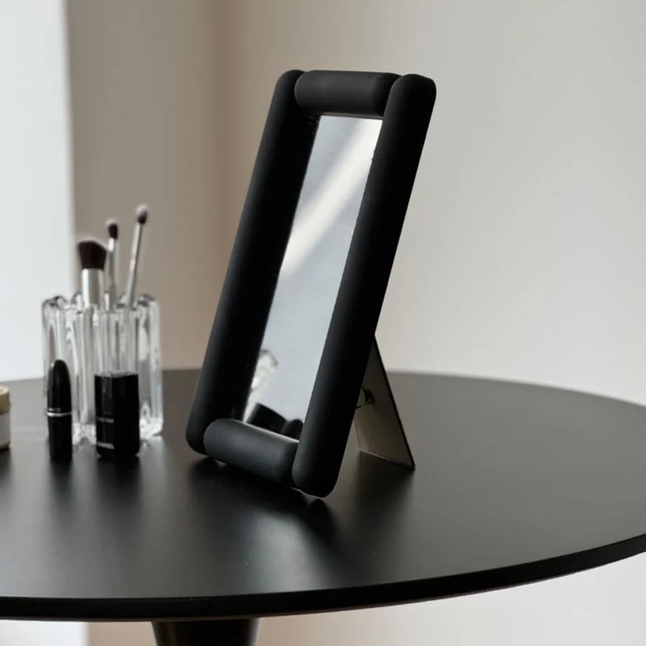 Side view showing the stand of the black rounded frame vanity mirror. - RoomDen