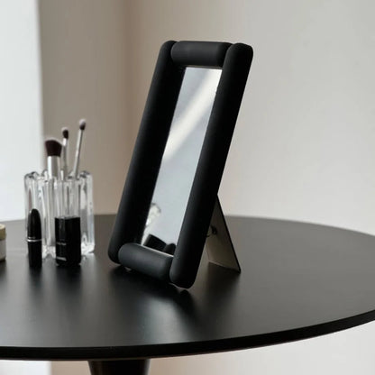 Side view showing the stand of the black rounded frame vanity mirror. - RoomDen