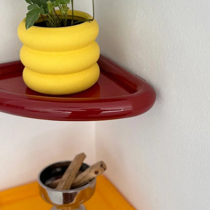 Detailed view of the glossy red finish on the Curved Corner Shelf, with a yellow shelf and decor below it. - RoomDen