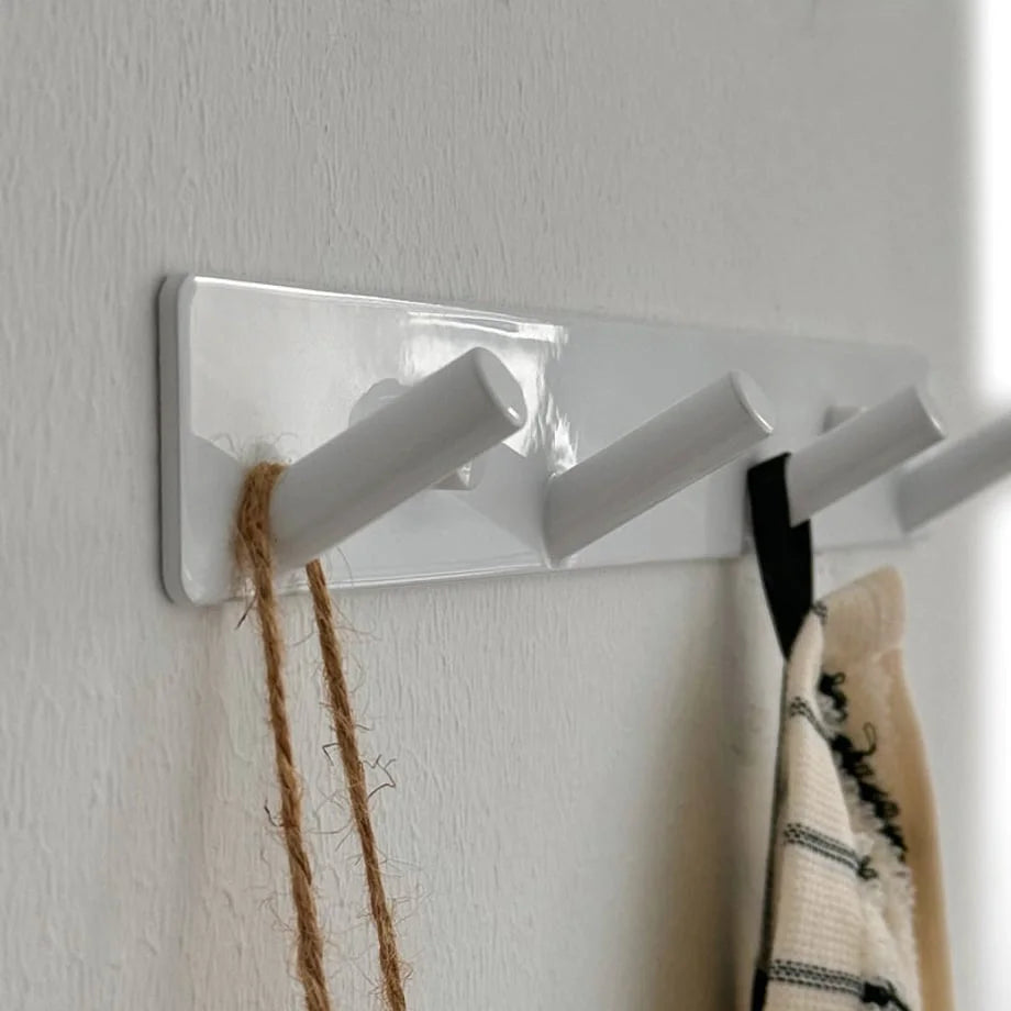 Close-up of the glossy white wall hooks showing the clean lines and peg shape - RoomDen.