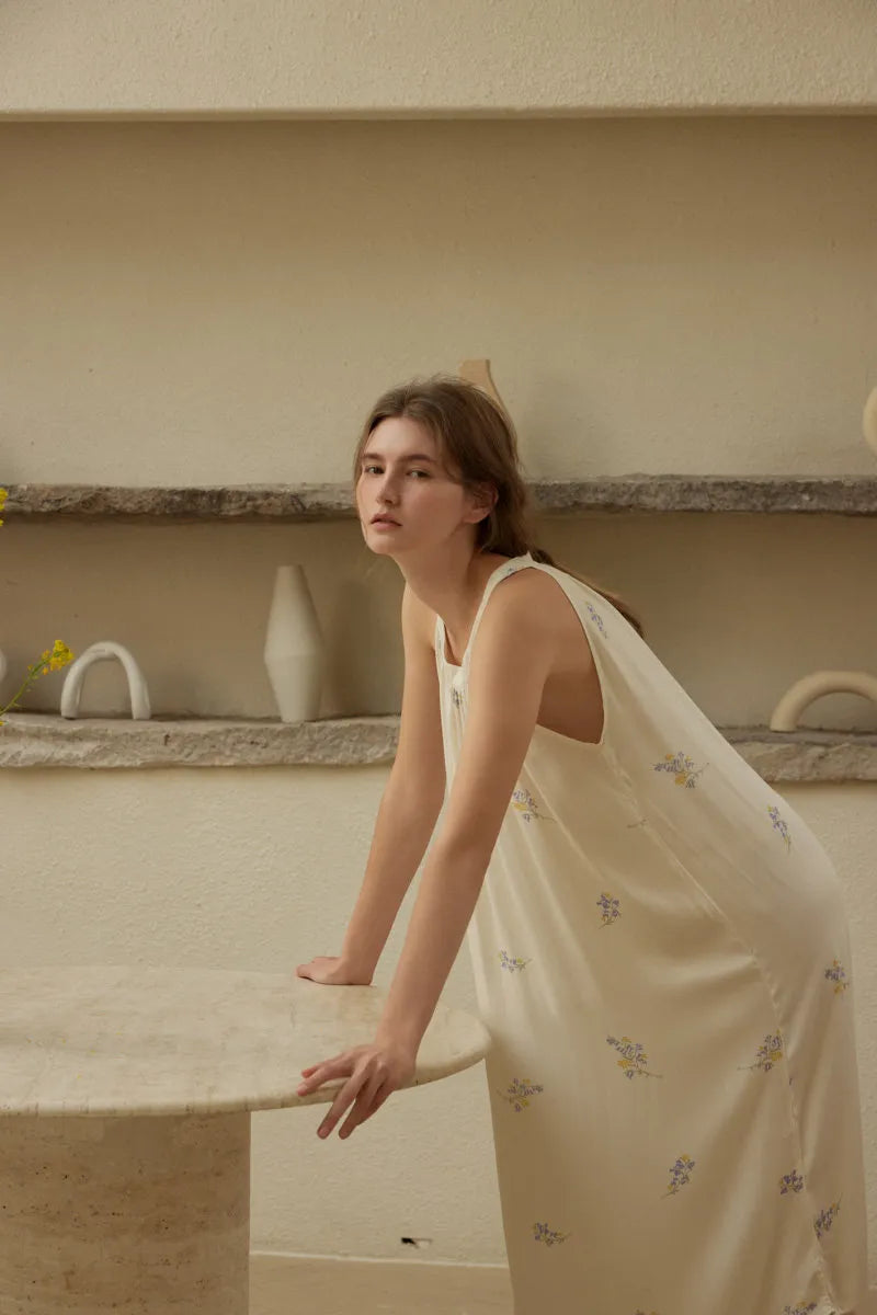 Side view of woman leaning on table showing silky fabric drape of floral nightgown - RoomDen