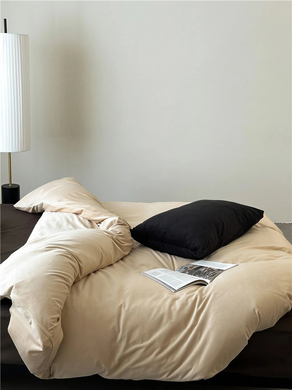 A minimalist bedroom scene featuring the Warm Beige velvet bedding set with a contrasting black pillow. - RoomDen