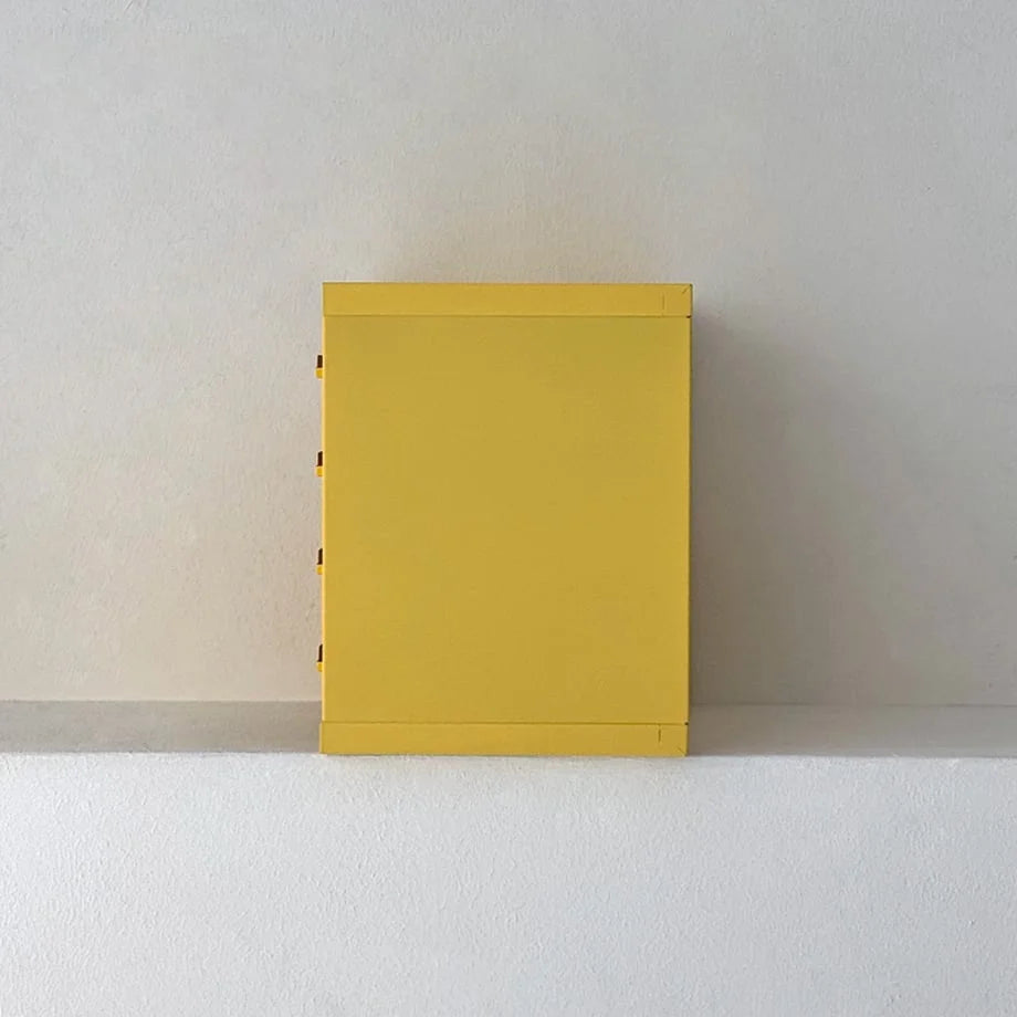 Side profile view of the Sunny Yellow metal desktop organizer against a white wall - RoomDen.