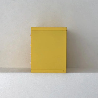 Side profile view of the Sunny Yellow metal desktop organizer against a white wall - RoomDen.