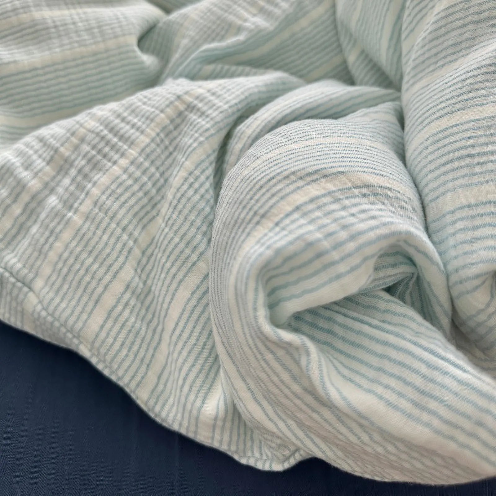 Detailed close-up of the rumpled, soft folds of the cyan pinstripe washed cotton bedding fabric.