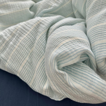 Detailed close-up of the rumpled, soft folds of the cyan pinstripe washed cotton bedding fabric.